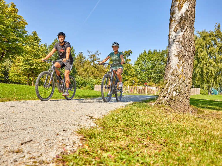 Aktive Gäste fahren mit dem Fahrrad auf einem idyllischen Weg rund um das Hotel bei Bad Griesbach.